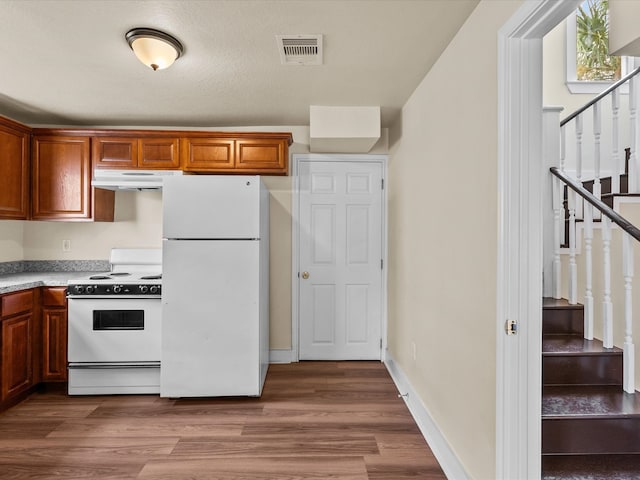 kitchen with light hardwood / wood-style floors, a textured ceiling, and white appliances