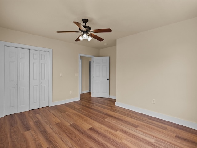 unfurnished bedroom with ceiling fan, a closet, and light wood-type flooring