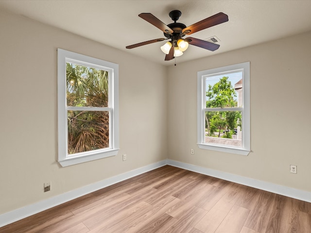 unfurnished room with a wealth of natural light, ceiling fan, and light hardwood / wood-style flooring