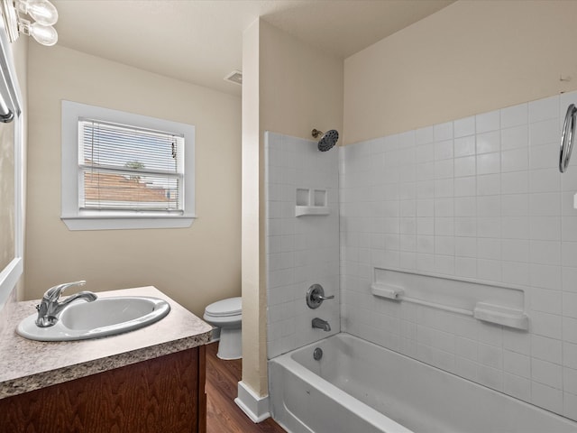 full bathroom with hardwood / wood-style floors, vanity, toilet, and tiled shower / bath combo