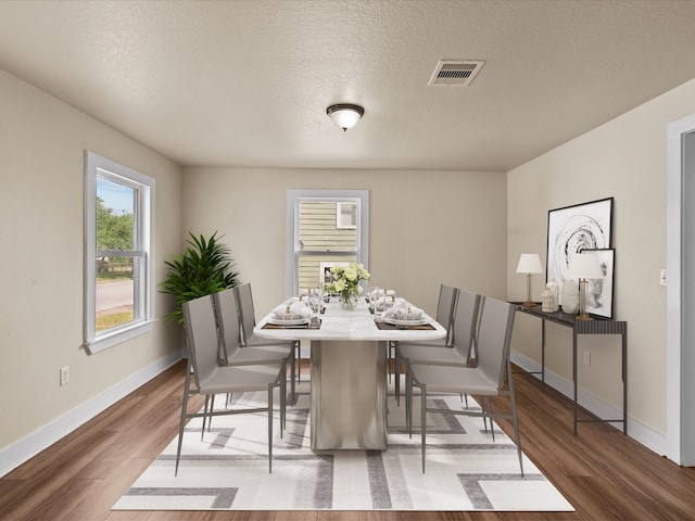 dining room with wood-type flooring and a textured ceiling