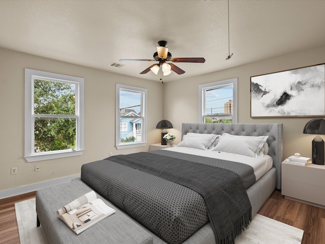 bedroom with multiple windows, hardwood / wood-style flooring, and ceiling fan