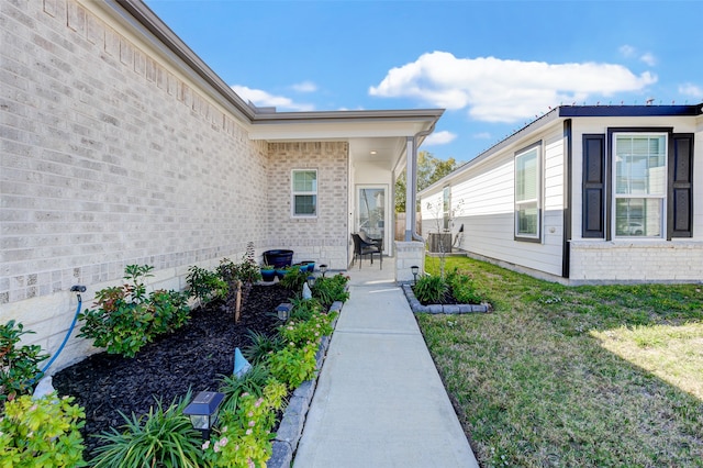 view of exterior entry featuring central AC unit and a lawn