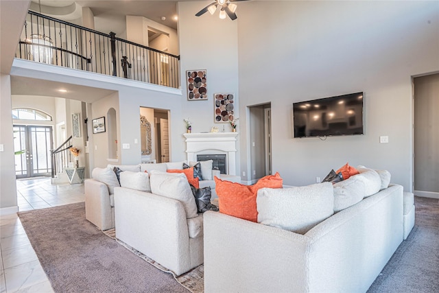 tiled living room featuring ceiling fan, a towering ceiling, and french doors