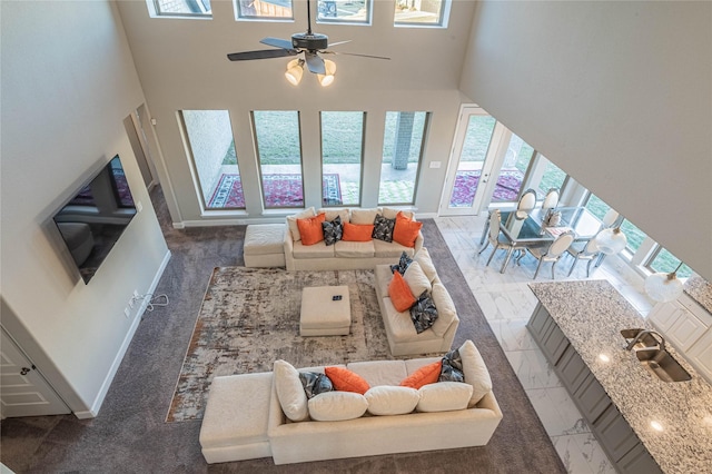 living room with ceiling fan, plenty of natural light, a towering ceiling, and sink