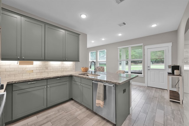 kitchen with dishwasher, sink, light wood-type flooring, light stone counters, and kitchen peninsula