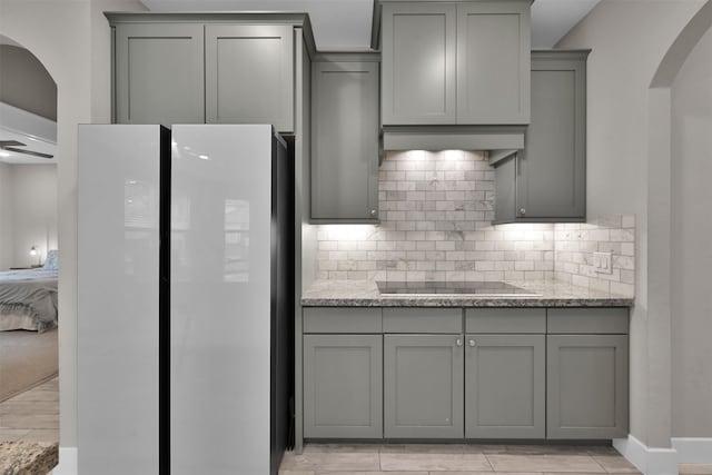 kitchen with gray cabinetry, light stone countertops, and black electric stovetop