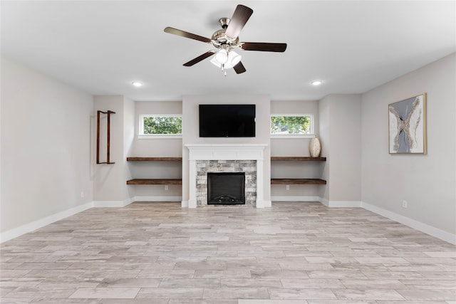 unfurnished living room with a fireplace, ceiling fan, light hardwood / wood-style flooring, and a healthy amount of sunlight