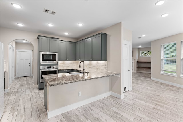 kitchen featuring gray cabinetry, sink, light stone countertops, appliances with stainless steel finishes, and light hardwood / wood-style floors