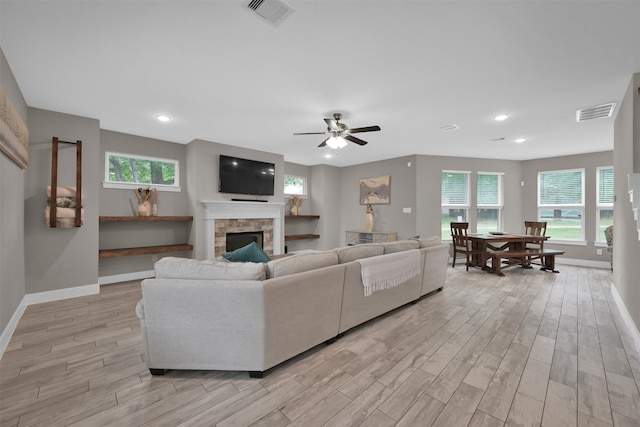 living room featuring ceiling fan, light hardwood / wood-style floors, a fireplace, and a wealth of natural light