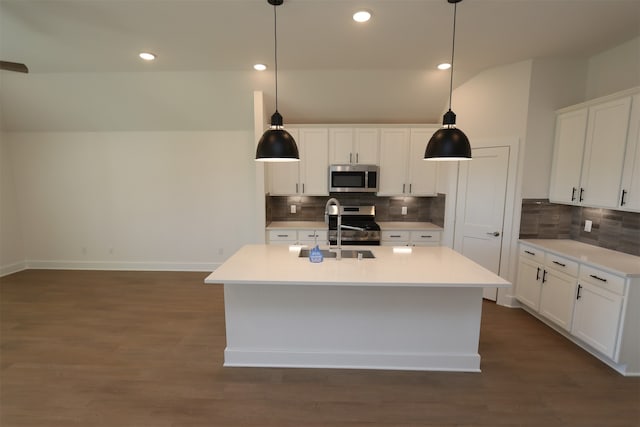 kitchen with dark wood-type flooring, hanging light fixtures, a center island with sink, white cabinets, and appliances with stainless steel finishes