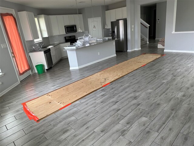 kitchen with white cabinets, a center island, stainless steel appliances, light hardwood / wood-style floors, and decorative backsplash