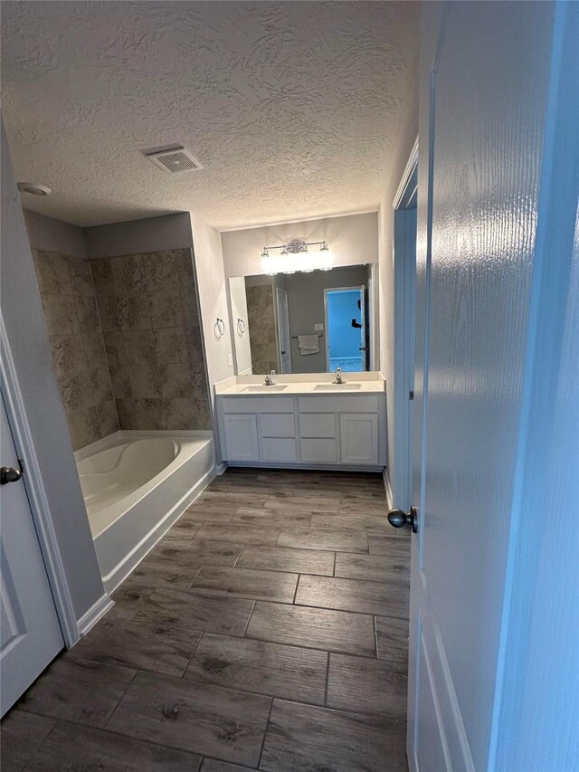 bathroom with a textured ceiling and double sink vanity