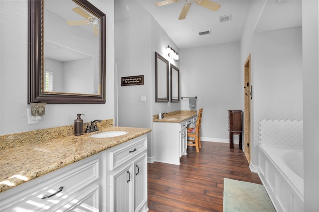 bathroom with dual bowl vanity, ceiling fan, hardwood / wood-style floors, and a tub