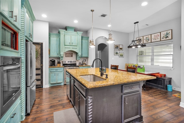 kitchen with decorative light fixtures, stainless steel appliances, dark hardwood / wood-style flooring, an island with sink, and sink