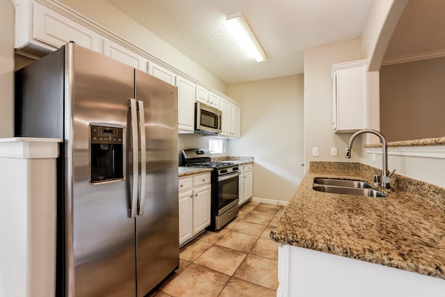 kitchen with appliances with stainless steel finishes, sink, stone counters, and white cabinetry