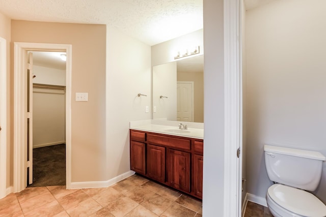 bathroom featuring a textured ceiling, toilet, and vanity