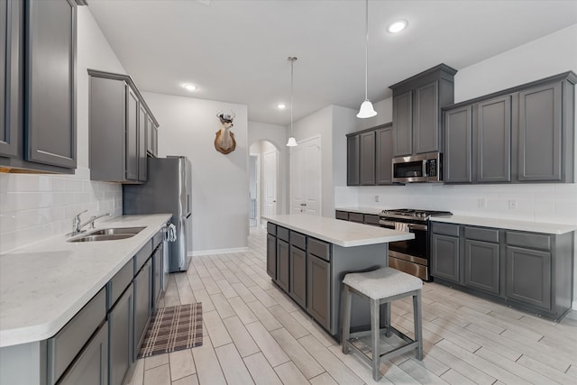 kitchen featuring decorative light fixtures, stainless steel appliances, gray cabinetry, and sink