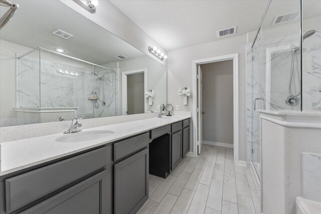 bathroom featuring vanity, an enclosed shower, and a textured ceiling