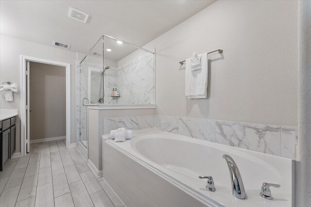 bathroom with plus walk in shower, a textured ceiling, and vanity