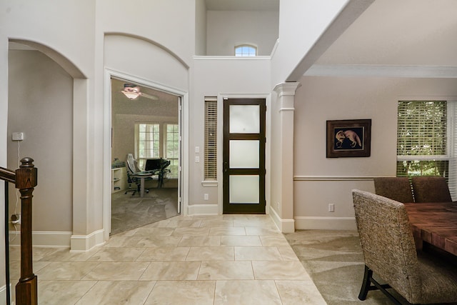 foyer entrance with ornate columns, light tile patterned floors, and a high ceiling