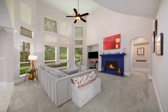 carpeted living room with ceiling fan, plenty of natural light, and high vaulted ceiling