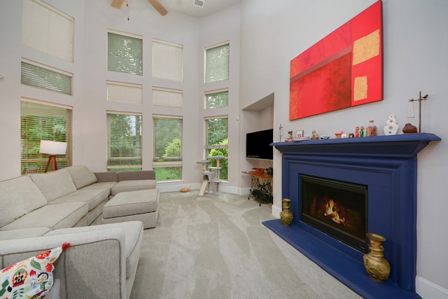 living room with carpet flooring, a towering ceiling, and ceiling fan