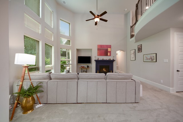 living room with carpet, plenty of natural light, ceiling fan, and a towering ceiling