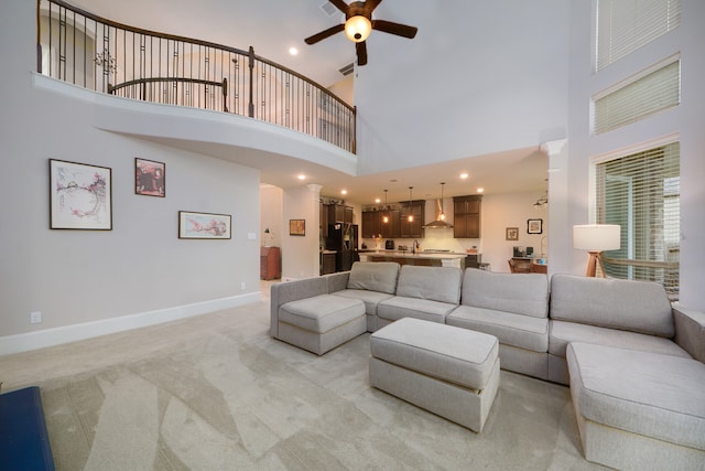 living room with light colored carpet, ceiling fan, and a towering ceiling