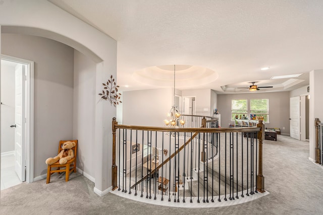 hallway with a chandelier, a raised ceiling, and carpet floors