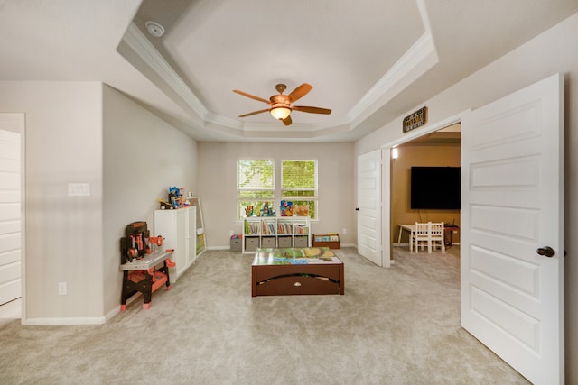 carpeted living room with ceiling fan and a tray ceiling