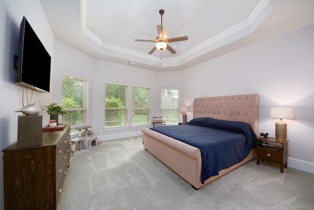 carpeted bedroom with ceiling fan, a raised ceiling, and crown molding