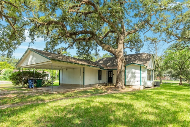 rear view of property featuring a carport, central air condition unit, and a lawn