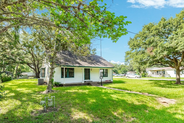 view of front facade featuring cooling unit, covered porch, and a front yard