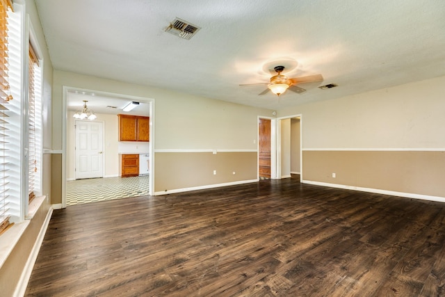 spare room with a textured ceiling, dark hardwood / wood-style floors, and ceiling fan with notable chandelier