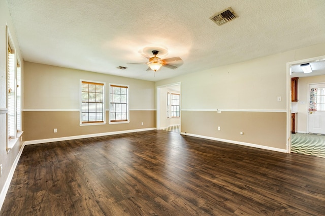 empty room with a textured ceiling, dark hardwood / wood-style flooring, and ceiling fan