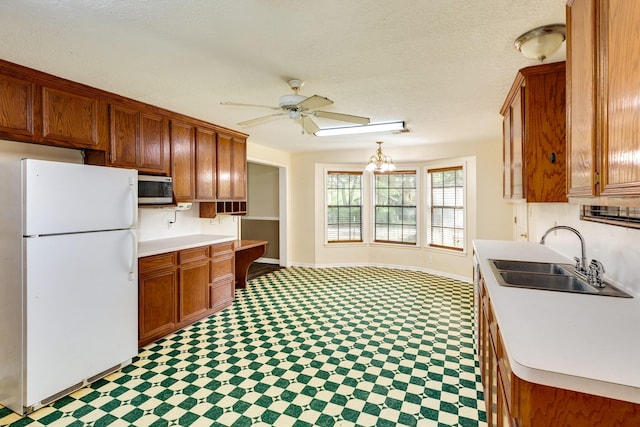 kitchen with ceiling fan with notable chandelier, a textured ceiling, white refrigerator, and sink