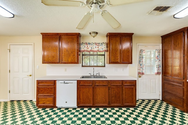 kitchen with white dishwasher, plenty of natural light, sink, and a textured ceiling