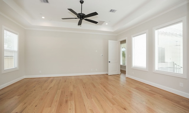 empty room featuring ceiling fan, light hardwood / wood-style floors, and a raised ceiling