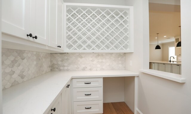 kitchen with hardwood / wood-style floors, white cabinetry, pendant lighting, and tasteful backsplash