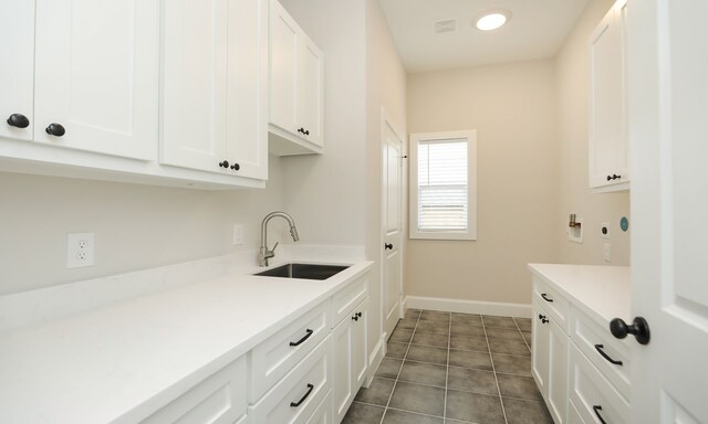 laundry area with cabinets, dark tile patterned floors, washer hookup, and sink