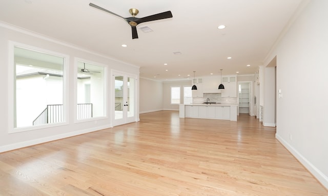 unfurnished living room with ornamental molding, sink, light wood-type flooring, and ceiling fan