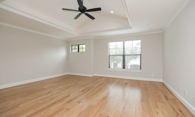 empty room with ornamental molding, a tray ceiling, light wood-type flooring, and ceiling fan