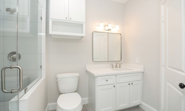 bathroom featuring vanity, toilet, and a shower with shower door