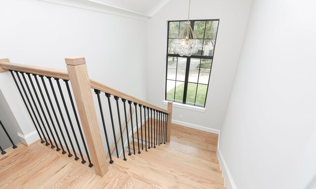 stairway featuring ornamental molding, a wealth of natural light, a chandelier, and hardwood / wood-style floors