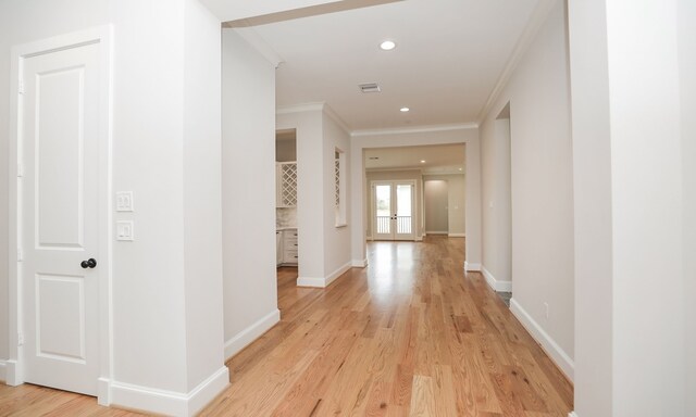 hallway featuring french doors, ornamental molding, and light hardwood / wood-style flooring