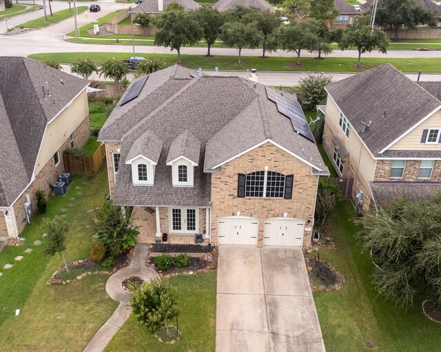 view of front of house with central AC unit, a garage, a front lawn, and solar panels