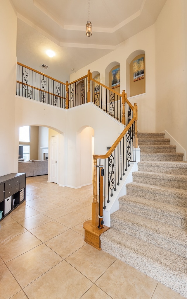 staircase featuring tile patterned flooring and a raised ceiling