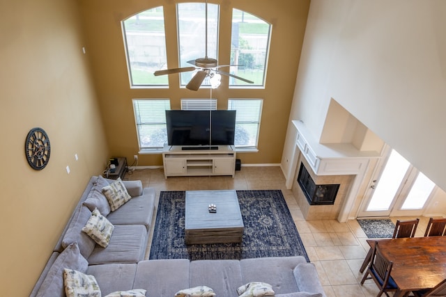 tiled living room featuring a high ceiling, a fireplace, ceiling fan, and a healthy amount of sunlight