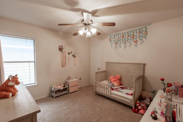 bedroom featuring a crib, multiple windows, carpet floors, and ceiling fan